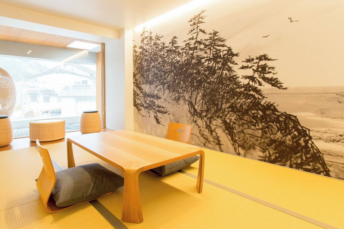 Een traditionele Japanse kamer met tatami vloeren, een lage houten tafel en een groot muurschildering.