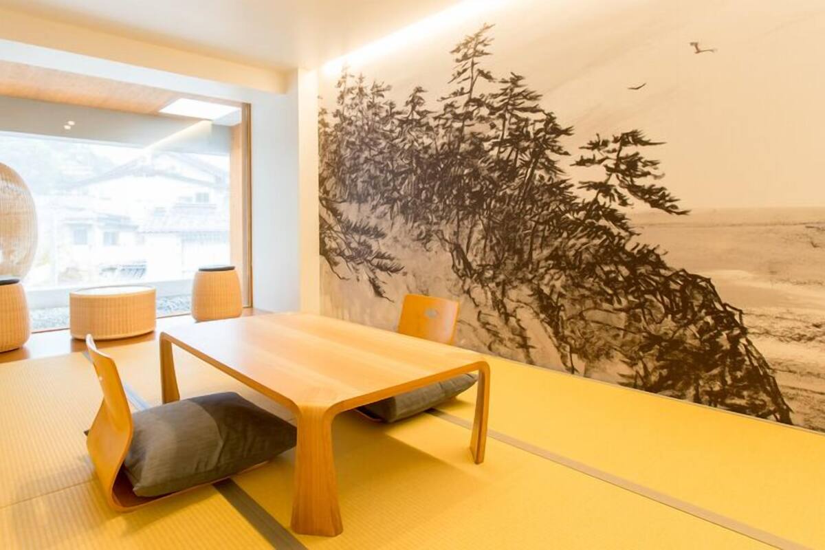 Een traditionele Japanse kamer met tatami vloerbedekking, een lage houten tafel en een groot wanddecoratie.