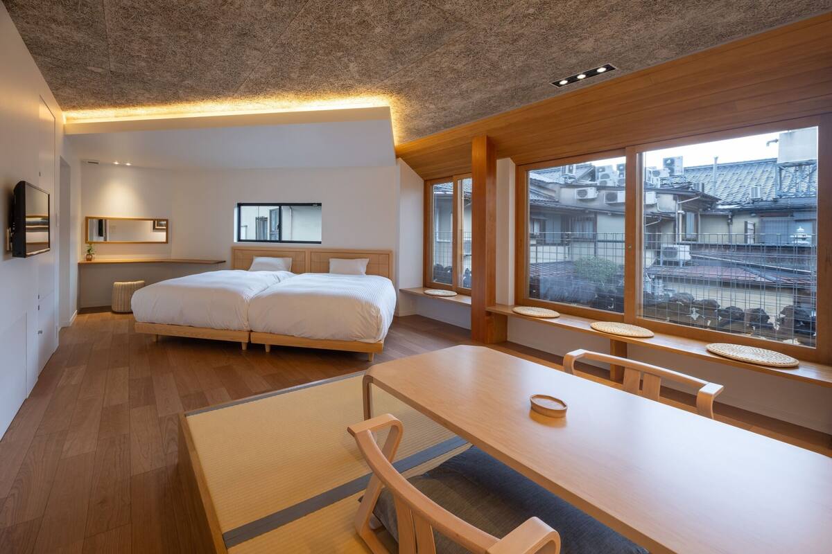 Een moderne hotelkamer met een groot bed, een eettafel en uitzicht op de stad.