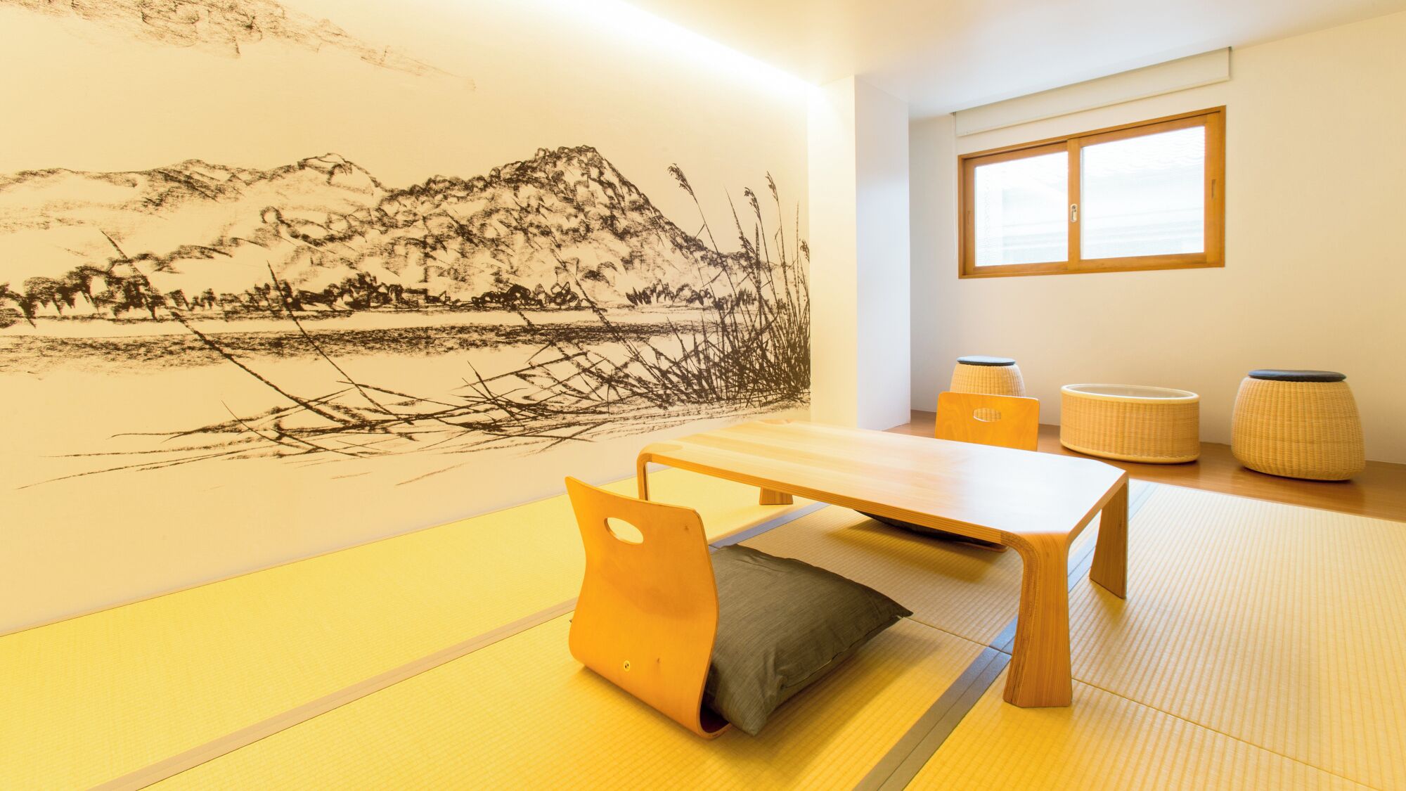 Een kamer met tatami matten, een lage tafel, kussens en een wanddecoratie.