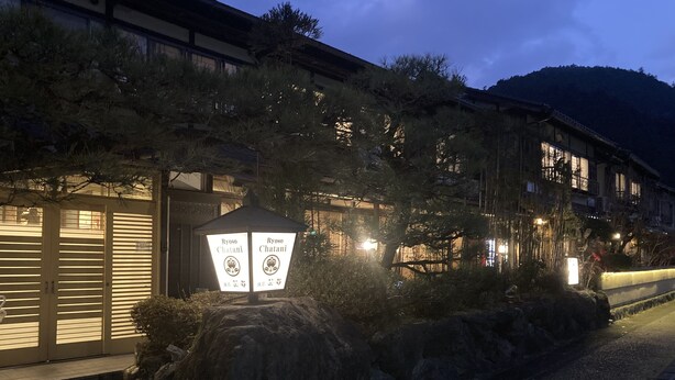 Un bâtiment traditionnel japonais, agrémenté d’une lanterne en pierre et d’une enseigne.