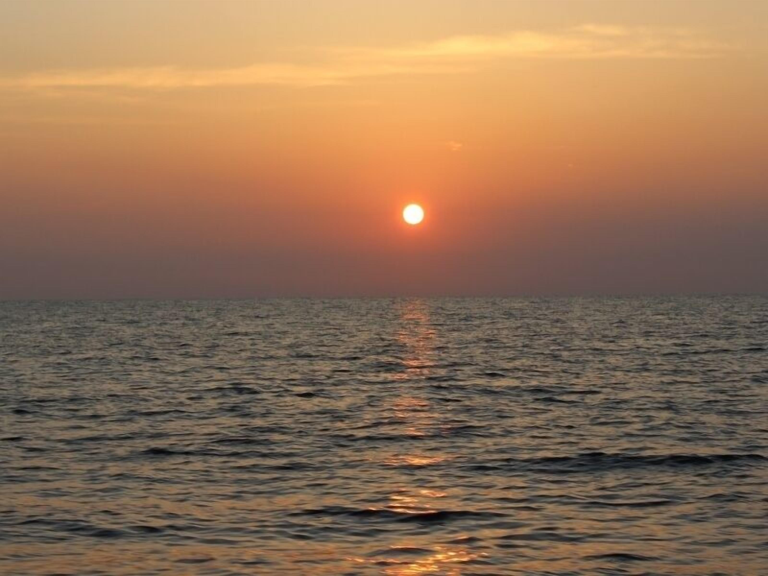 A sunset over a calm sea with no visible land or structures.