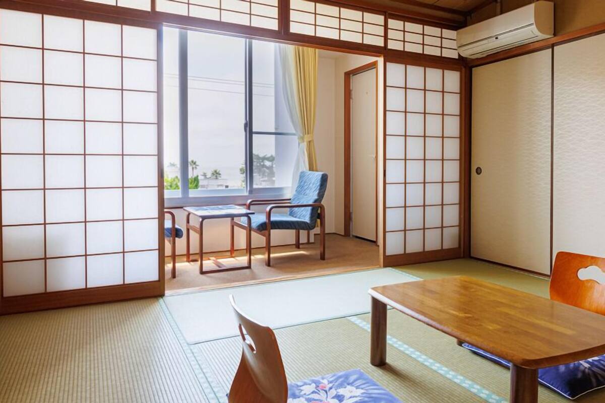 A traditional Japanese room with tatami flooring, a wooden table, and a sliding door.
