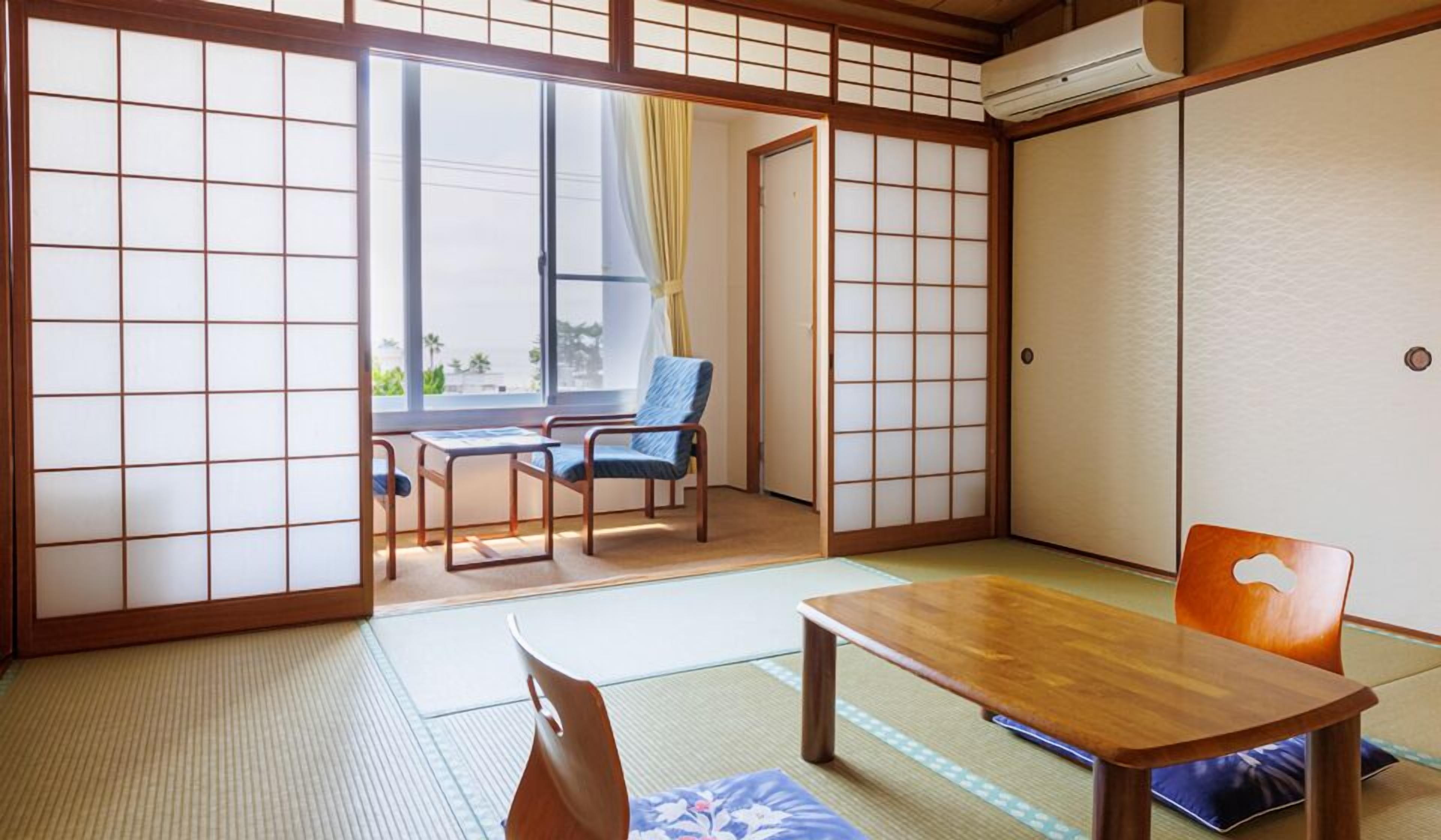 Une pièce de style japonais traditionnel, avec un sol recouvert de tatamis, une table en bois, une chaise et une porte coulissante.