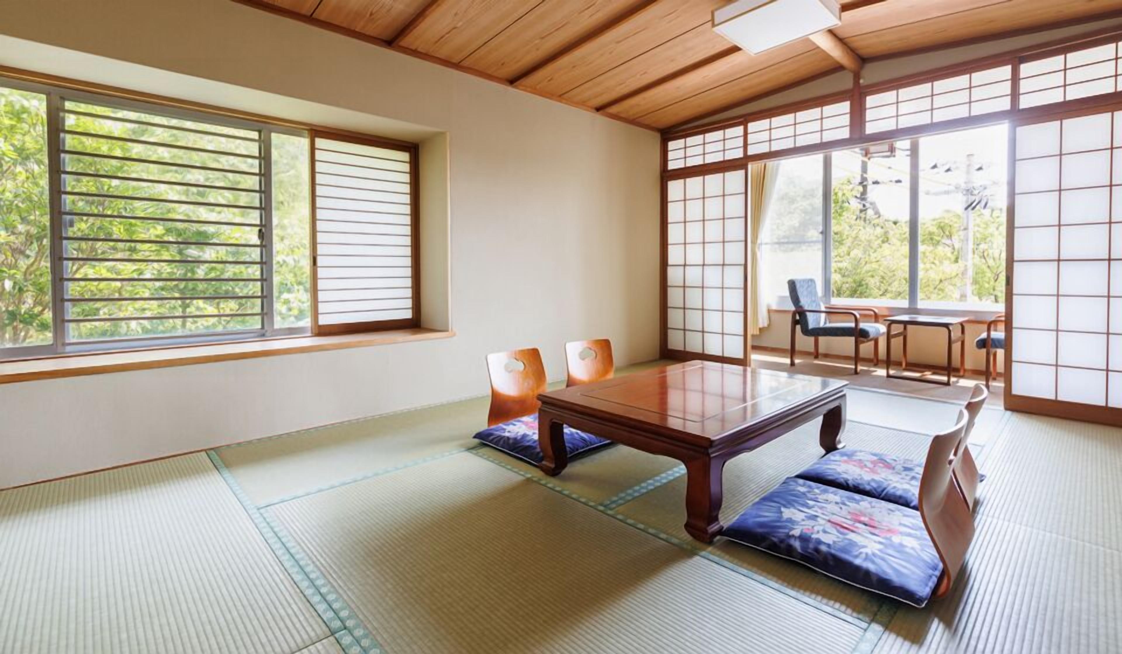 Une pièce de style japonais traditionnel, avec un sol recouvert de tatamis, une petite table en bois et des portes coulissantes.