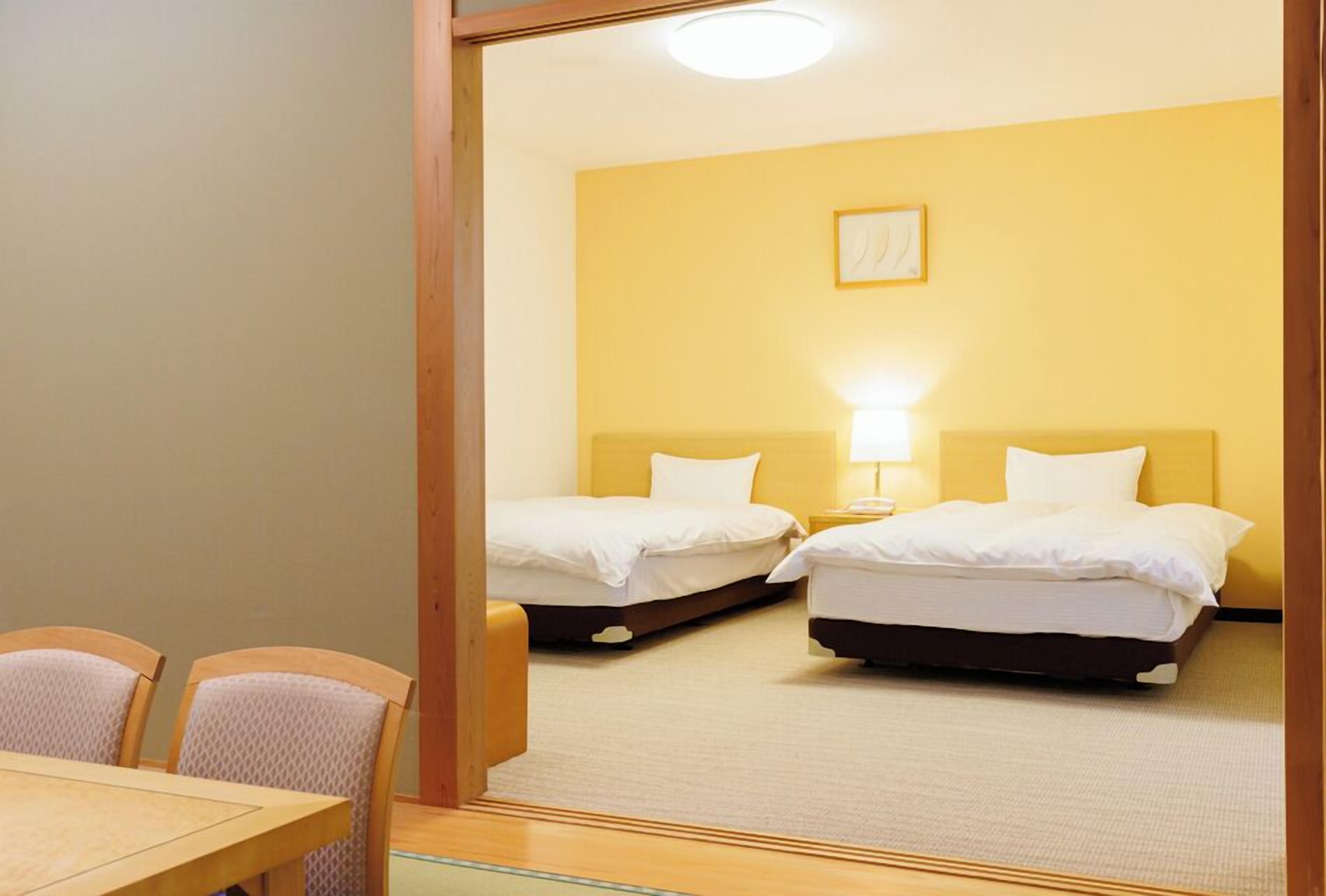 A hotel room with two beds, a small table, and chairs.