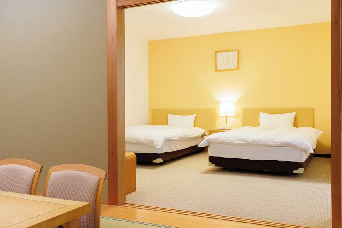 A hotel room with two beds, a small table, and chairs.