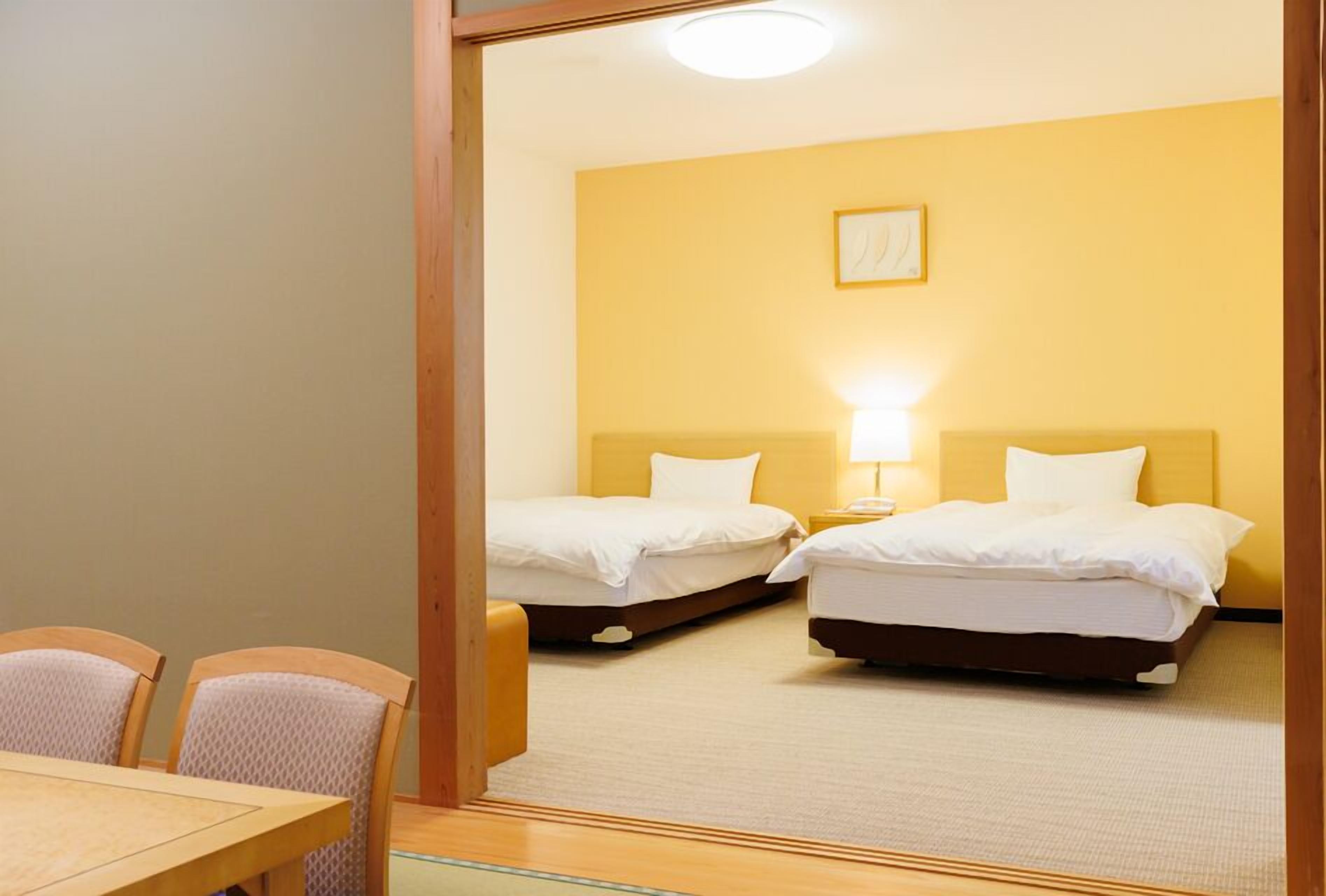 A hotel room with two beds, a dining table, and chairs.