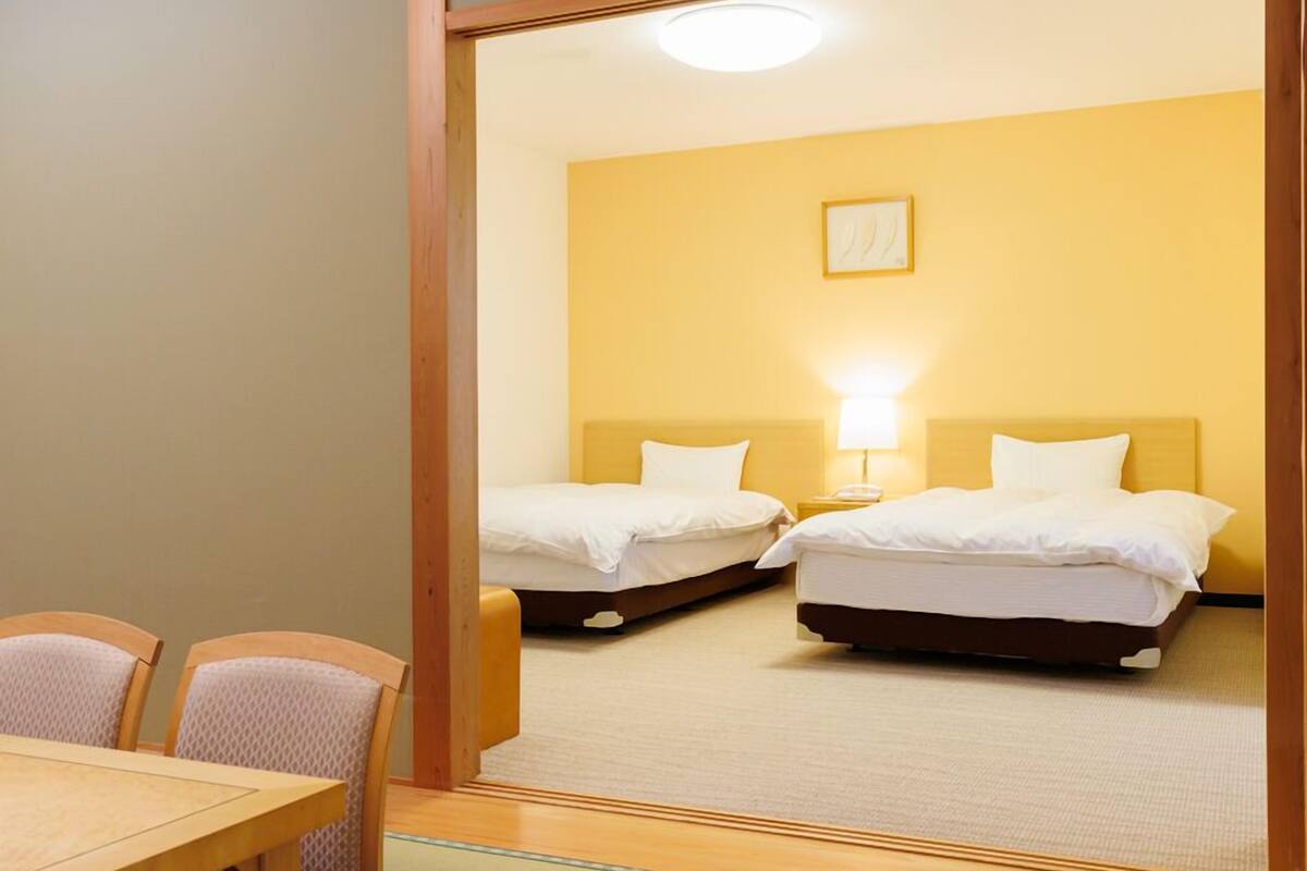A hotel room with two beds, a dining table, and chairs.