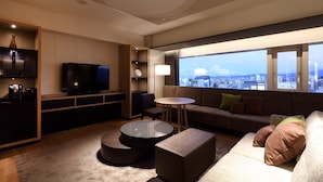 Una sala de estar moderna con televisor, sofá, mesa de centro y vistas a la ciudad.