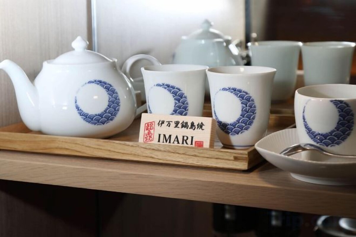 A tea set with a teapot, cups, and saucer on a wooden tray.