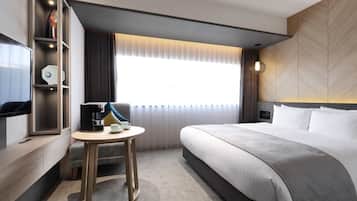 Une chambre d’hôtel avec un lit, un bureau doté d’une machine à café, une télévision et une fenêtre avec des rideaux.