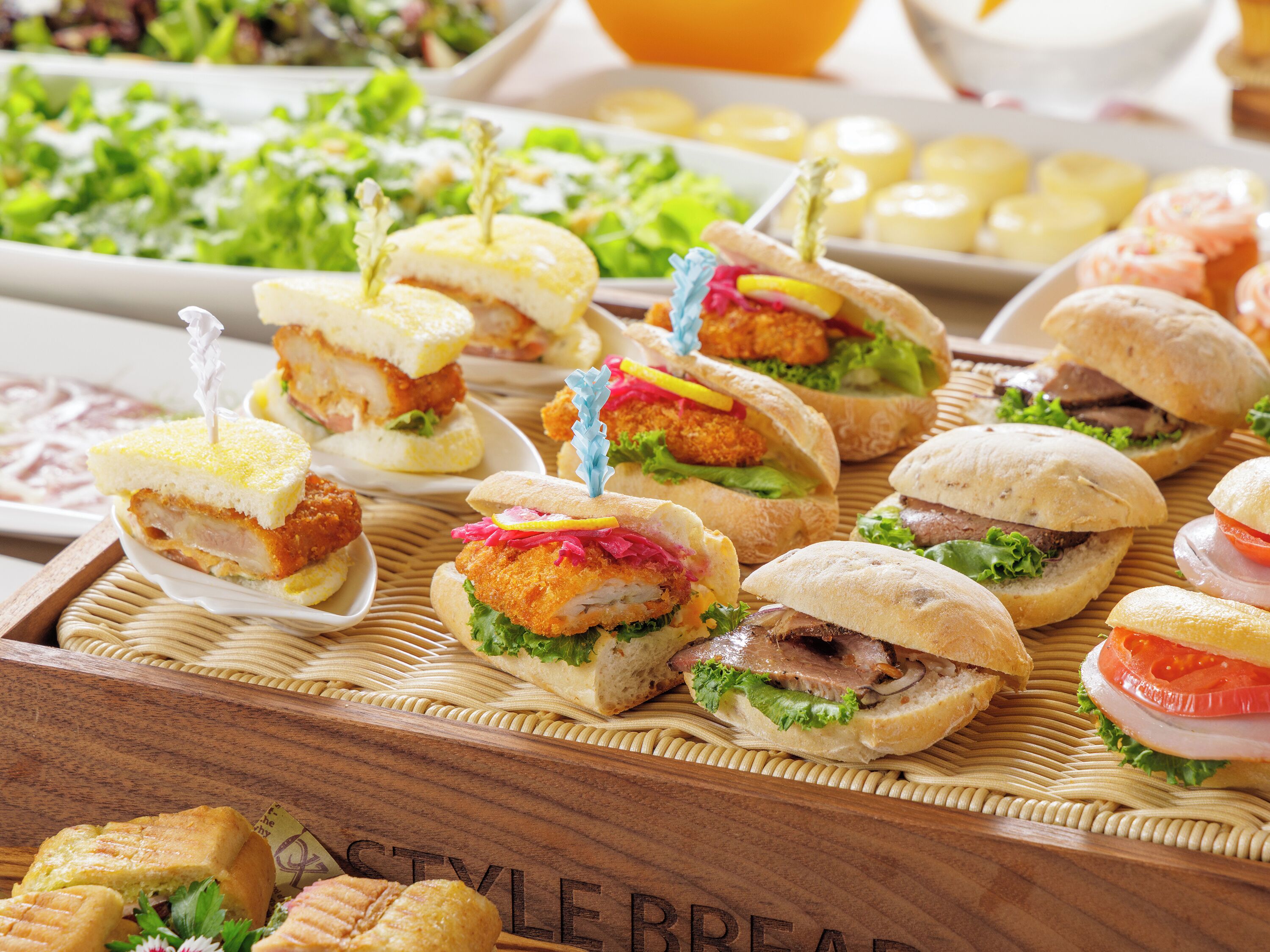 A variety of sandwiches and pastries on a wooden tray.