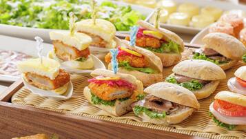 A variety of sandwiches and pastries on a wooden tray.