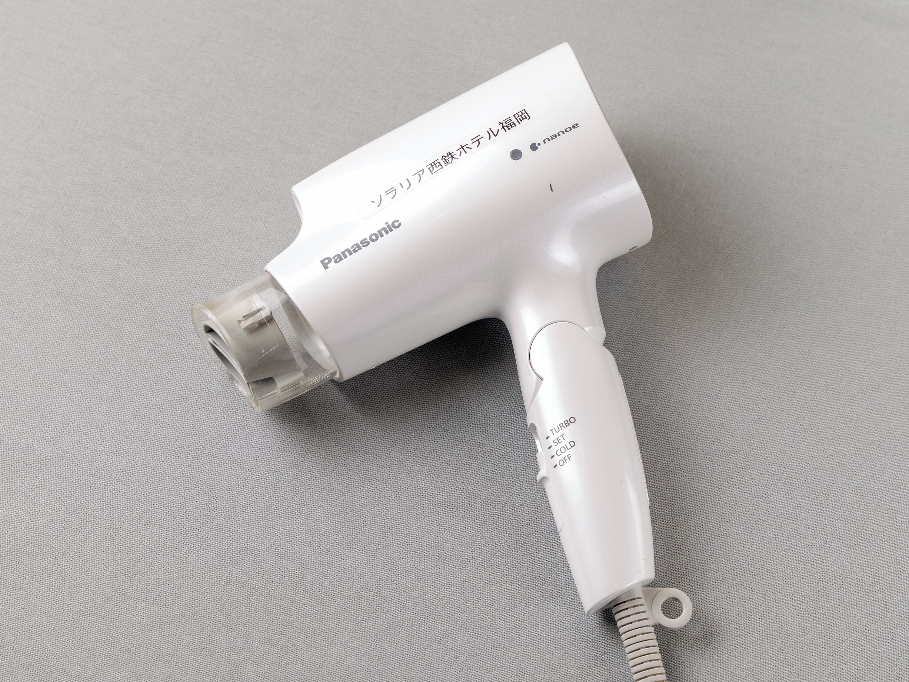 A Panasonic hair dryer with a clear nozzle and a cord.