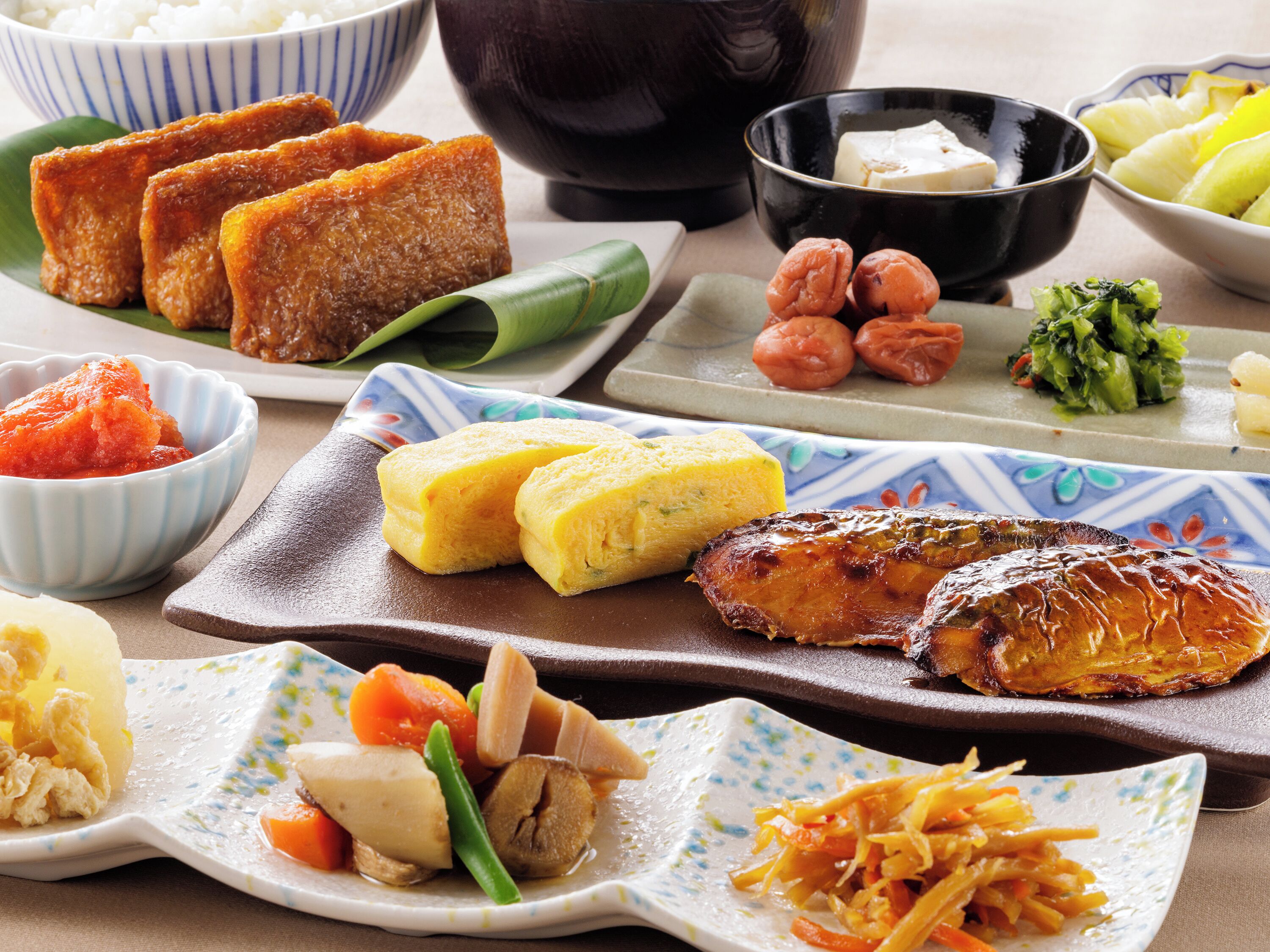 A variety of dishes including fried tofu, a grilled fish, and several side dishes on a table.