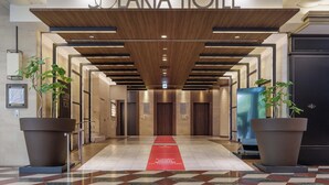 La entrada del Hotel Solaria con un diseño moderno, que cuenta con un techo de madera y una alfombra roja que conduce a la recepción.
