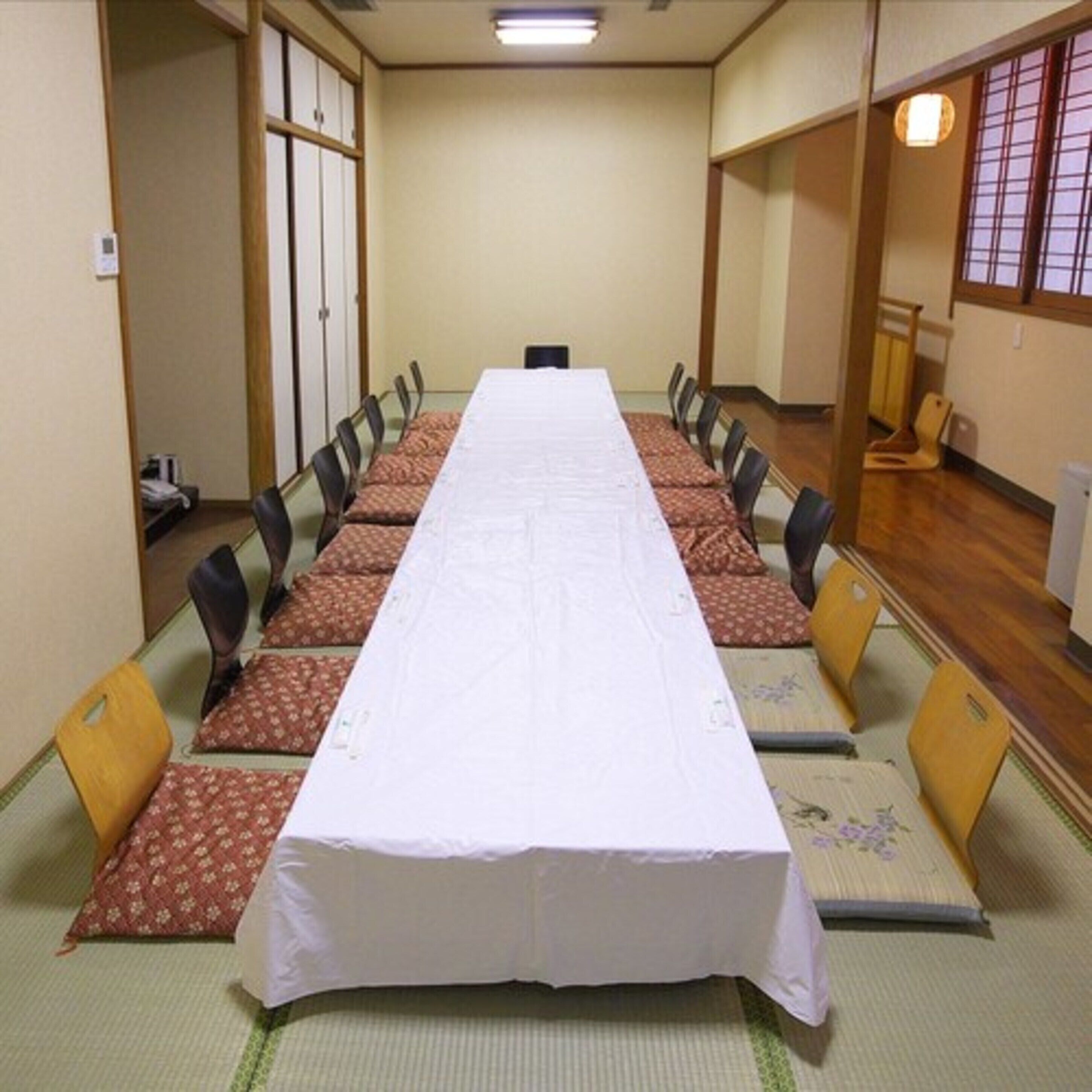 A conference room with a long table, chairs, and tatami mats.