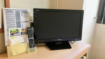 Un téléviseur posé sur un bureau en bois, avec une télécommande et une feuille de papier contenant du texte et des images.