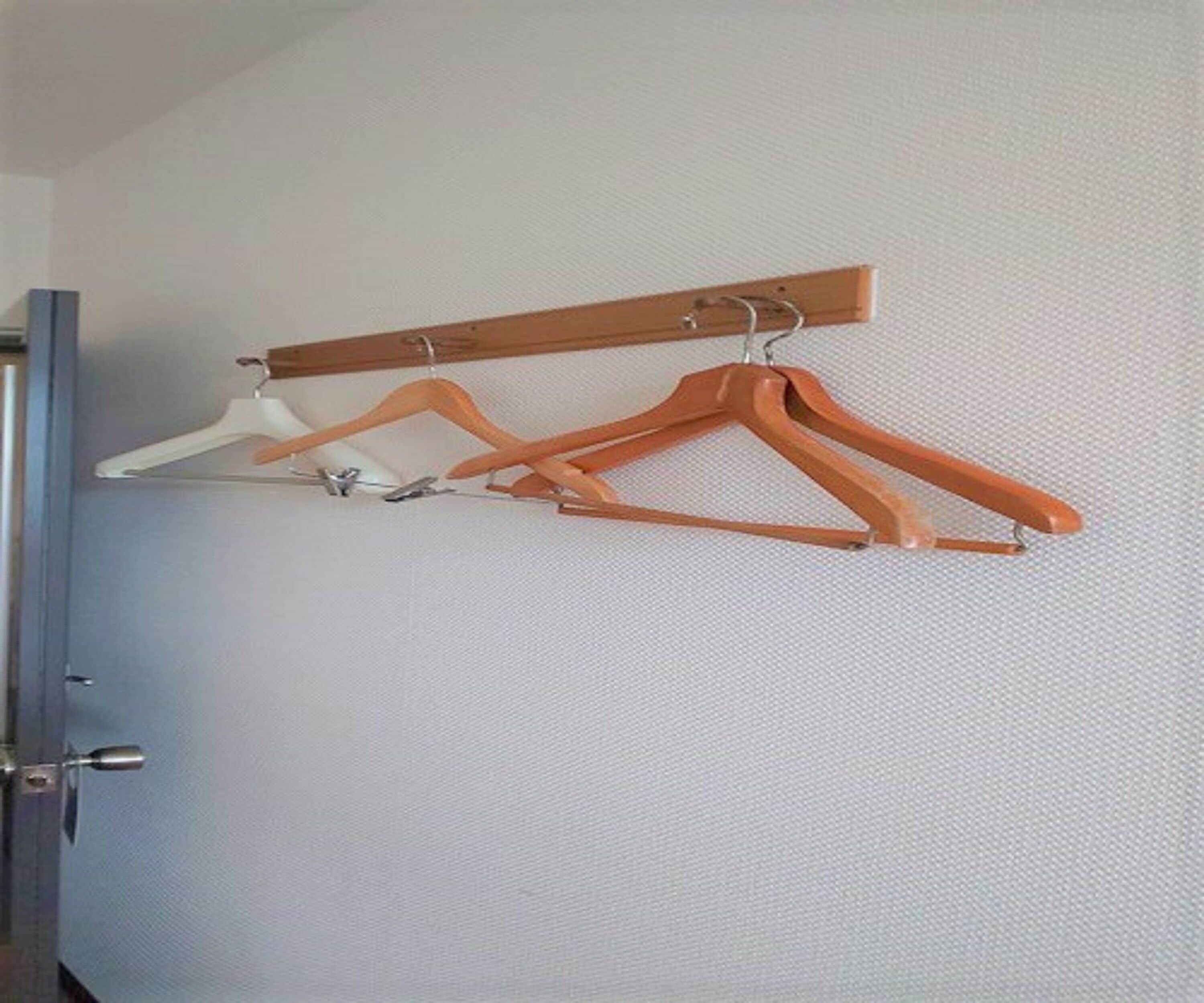 Una barra de madera para colgar en la pared con tres perchas.