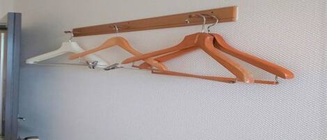 Una barra de madera para colgar en la pared con tres perchas.