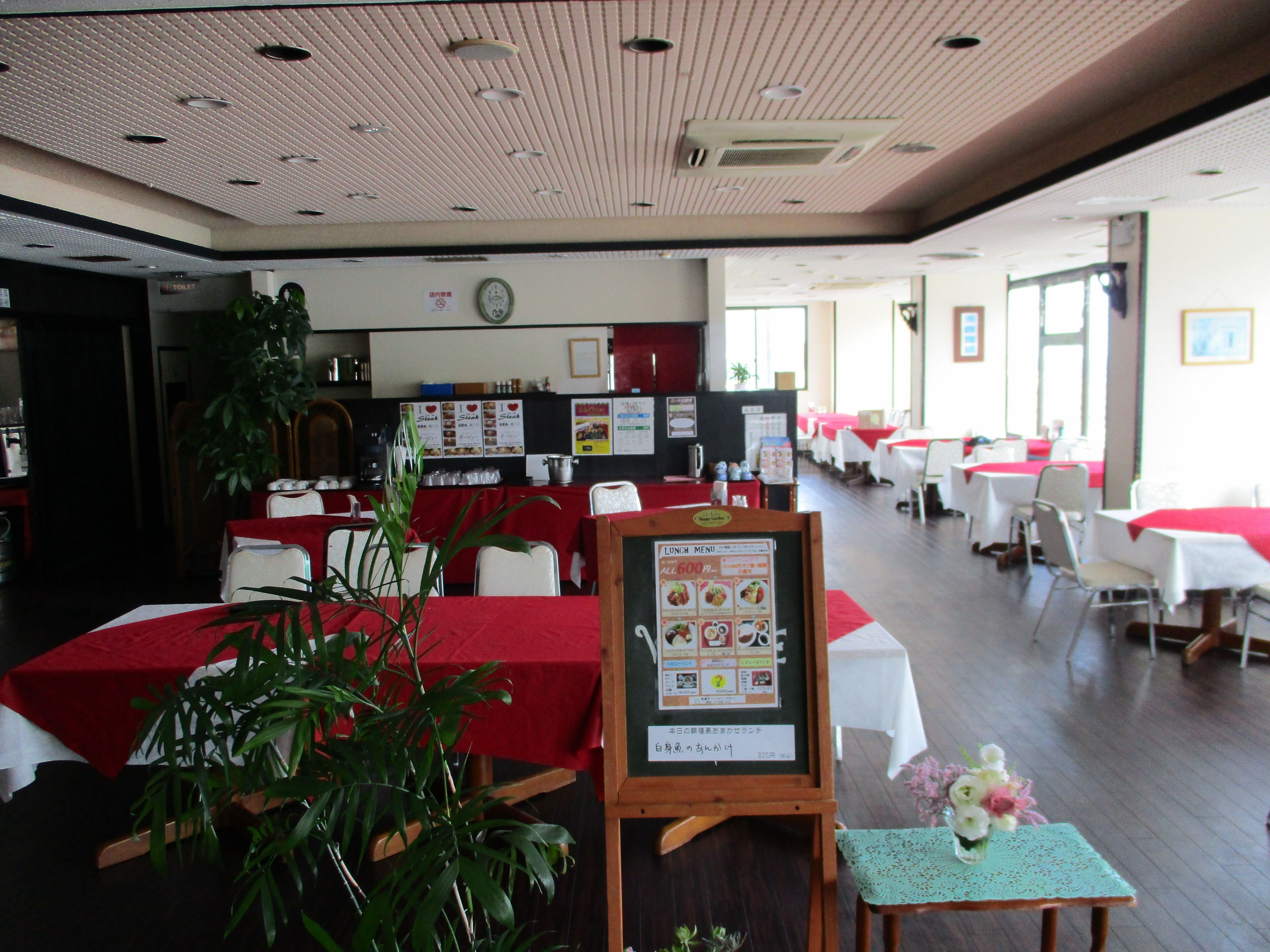 Un restaurant avec plusieurs tables, un tableau affichant le menu et une horloge au mur.
