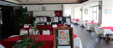 A restaurant with multiple tables, a menu board, and a clock on the wall.