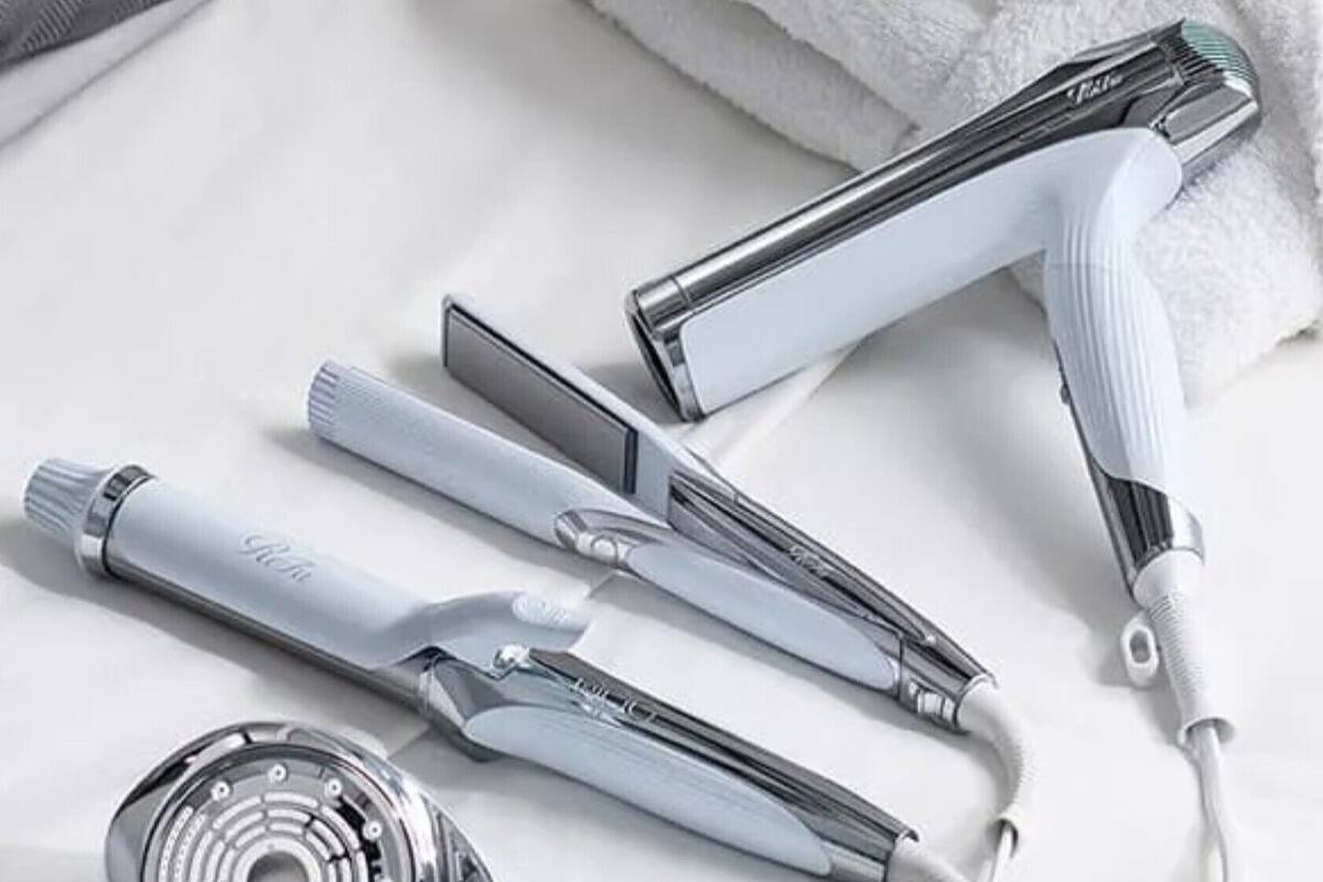 A hair straightener, a comb, and a curling iron on a white surface.