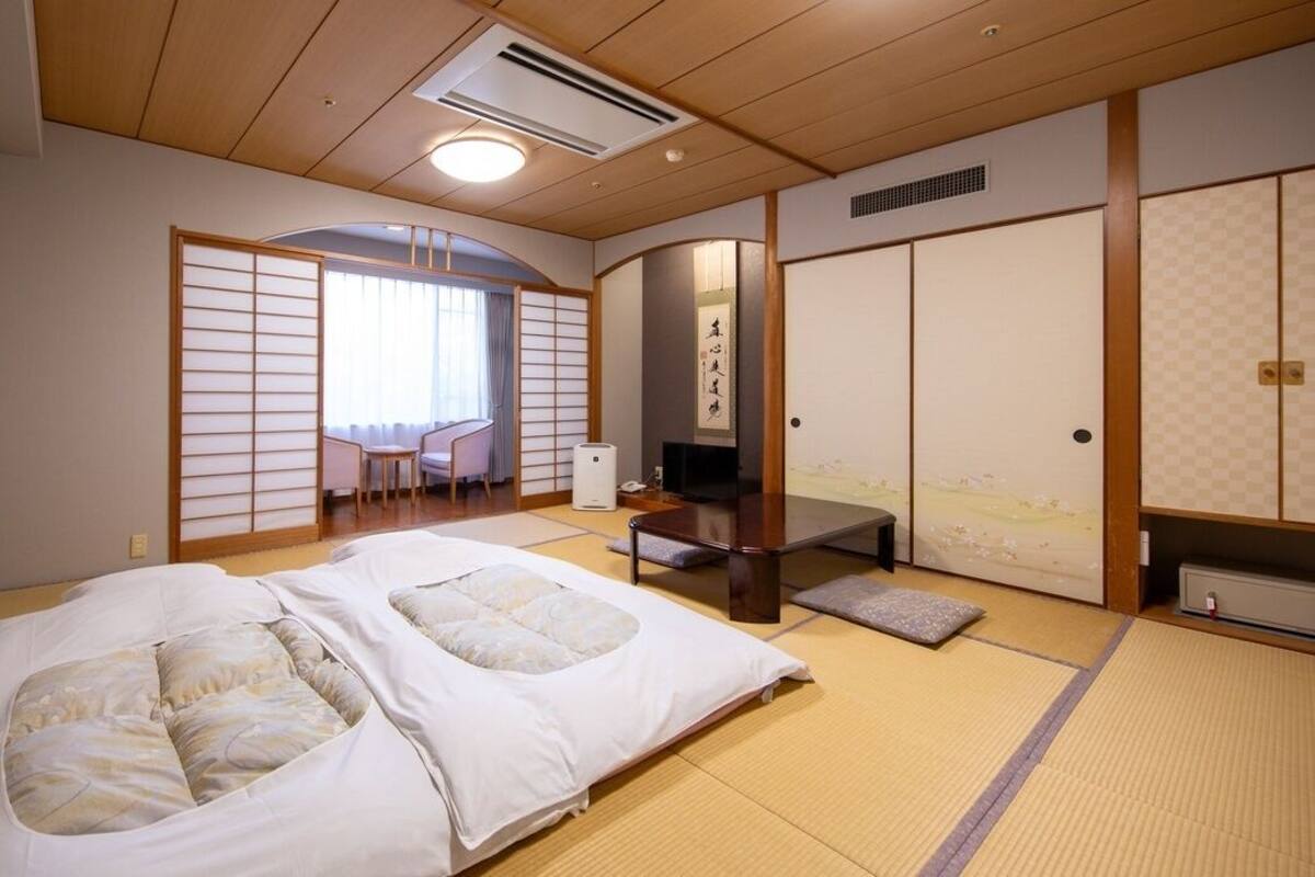 A traditional Japanese-style room with tatami flooring, a futon bed, a low table, and sliding doors.
