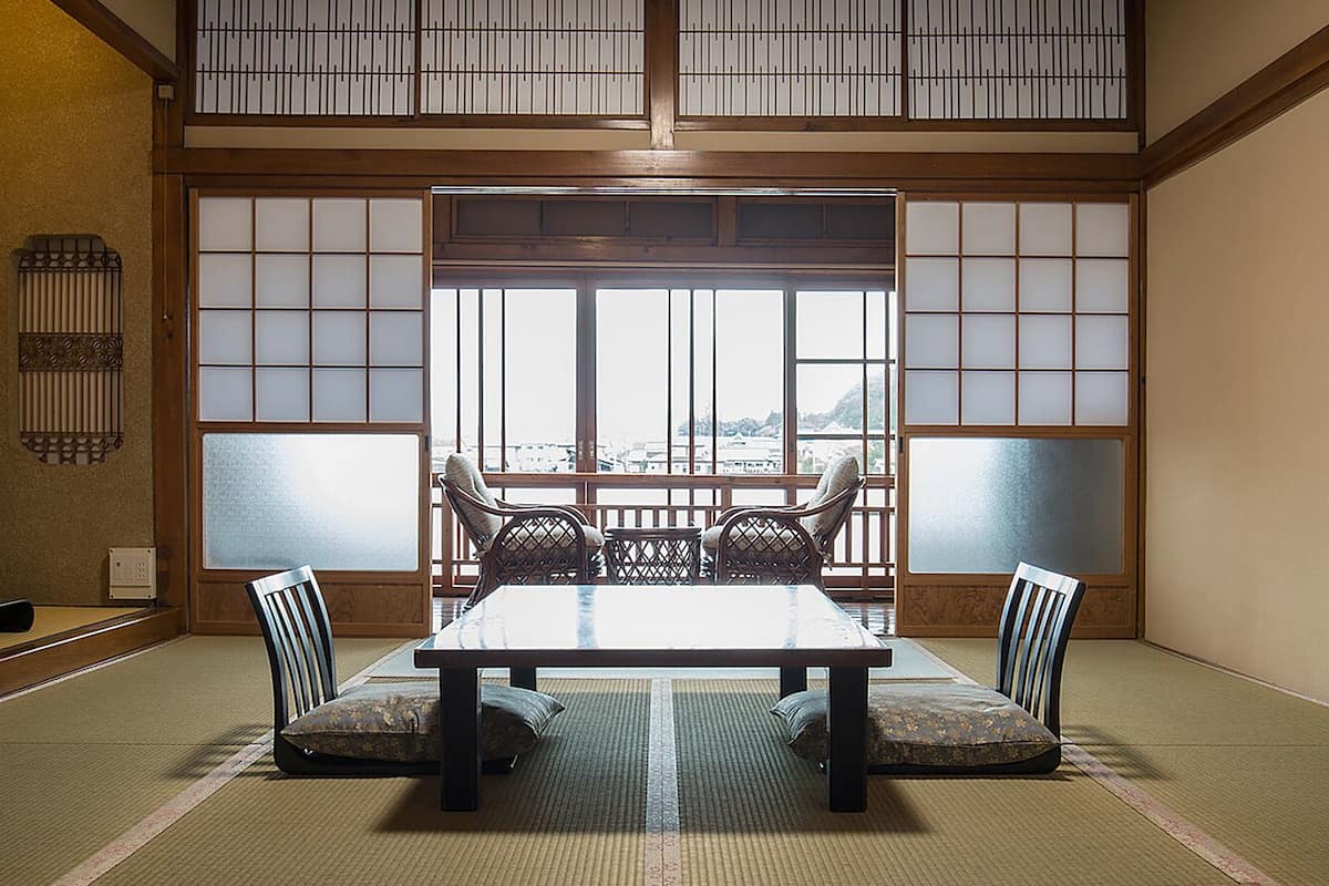 Una habitación japonesa tradicional con suelo de tatami, una mesa baja y puertas correderas shoji.