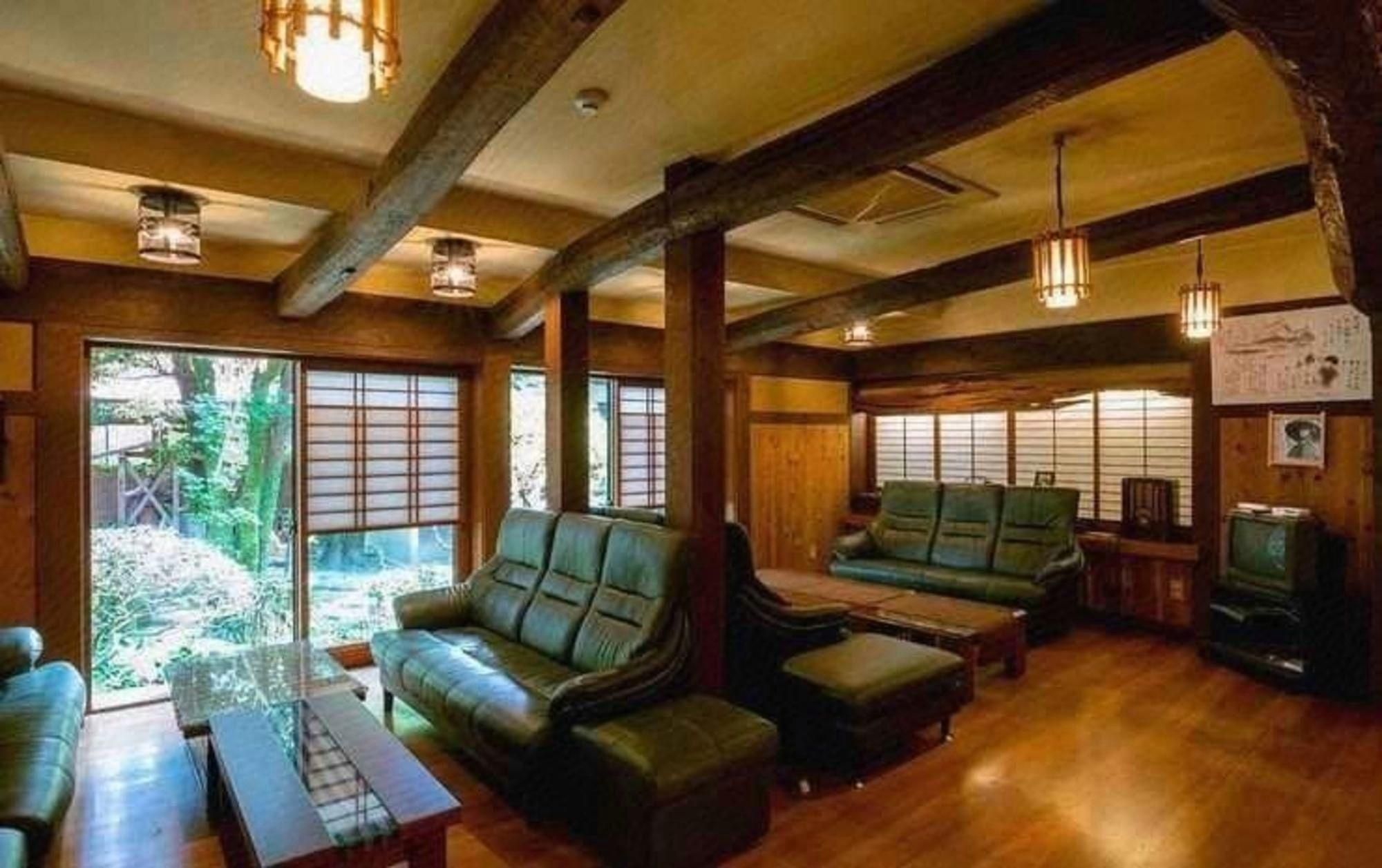 A room with a wooden ceiling, leather sofas, a wooden coffee table, and a television.