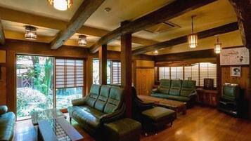A room with a wooden ceiling, leather sofas, a wooden coffee table, and a television.