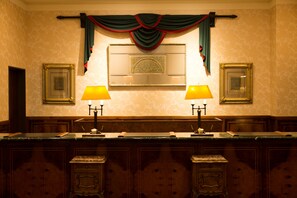 A bar area with two lamps, framed artwork, and a decorative drape. - Dukes Hotel Hakata (Fukuoka)
