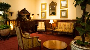A traditional room with a red carpet, wooden furniture, and framed artwork on the wall.