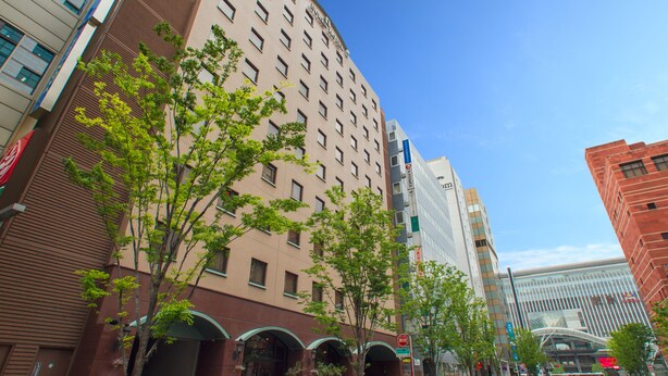 A multi-story hotel with a modern design, featuring a prominent entrance with arched windows and a clear view of the sky.