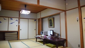 A traditional Japanese room with tatami flooring, a desk with electronic devices, and a painting on the wall. - Yamabe Hotel (Tenri)
