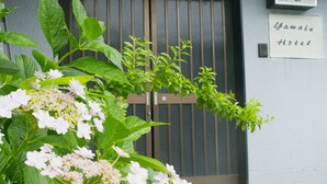 A hotel entrance with a wooden gate, a signboard with Japanese characters, and lush greenery in the foreground. - Yamabe Hotel (Tenri)