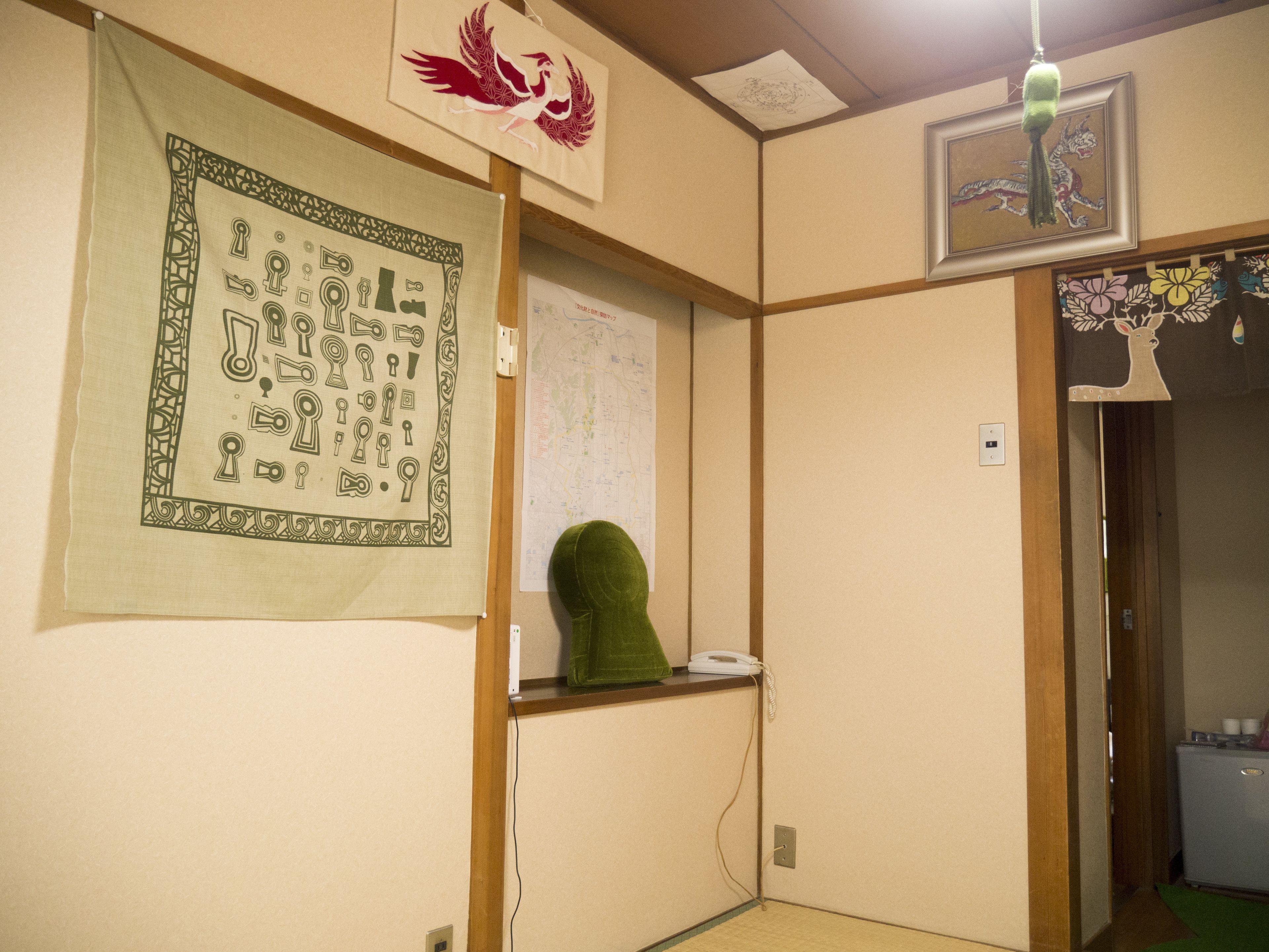 Una habitación con un mapa en la pared, un cojín verde y una obra de arte enmarcada de un pájaro.