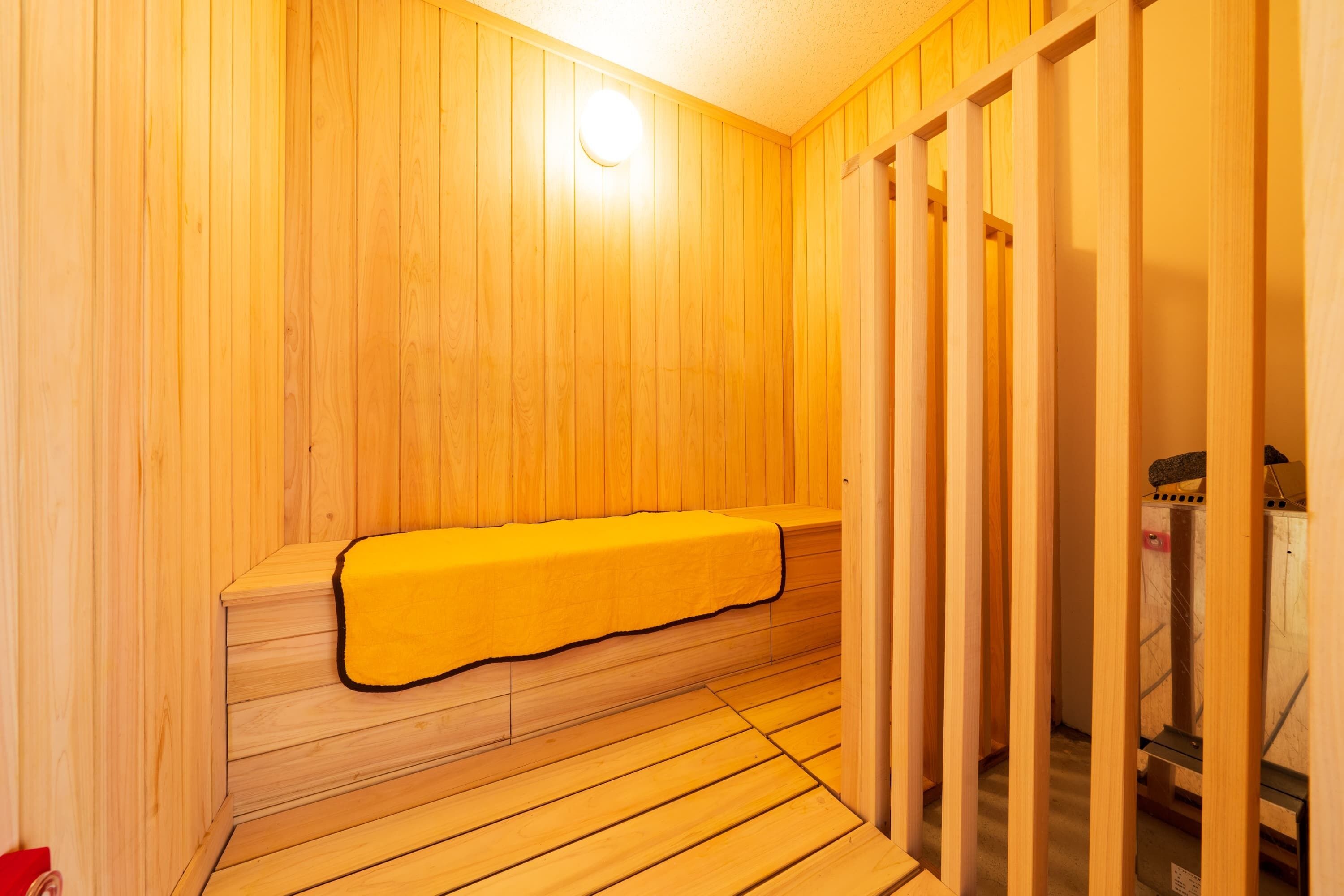 Una sauna de madera con bancos y un banco con funda amarilla.
