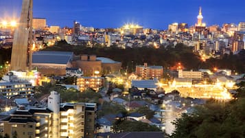 Un paisaje urbano al anochecer con edificios iluminados y una torre destacada.