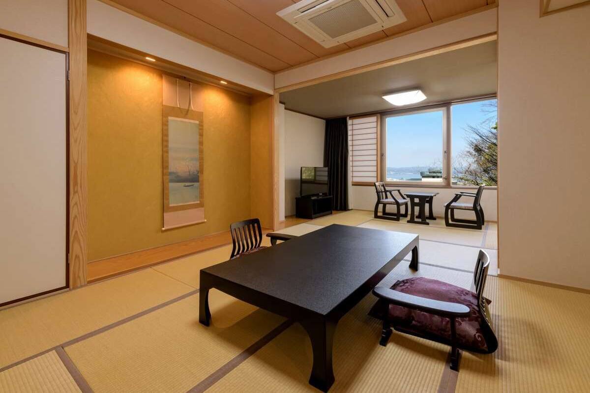 Una habitación japonesa tradicional con suelo de tatami, una mesa baja y un banco acolchado.