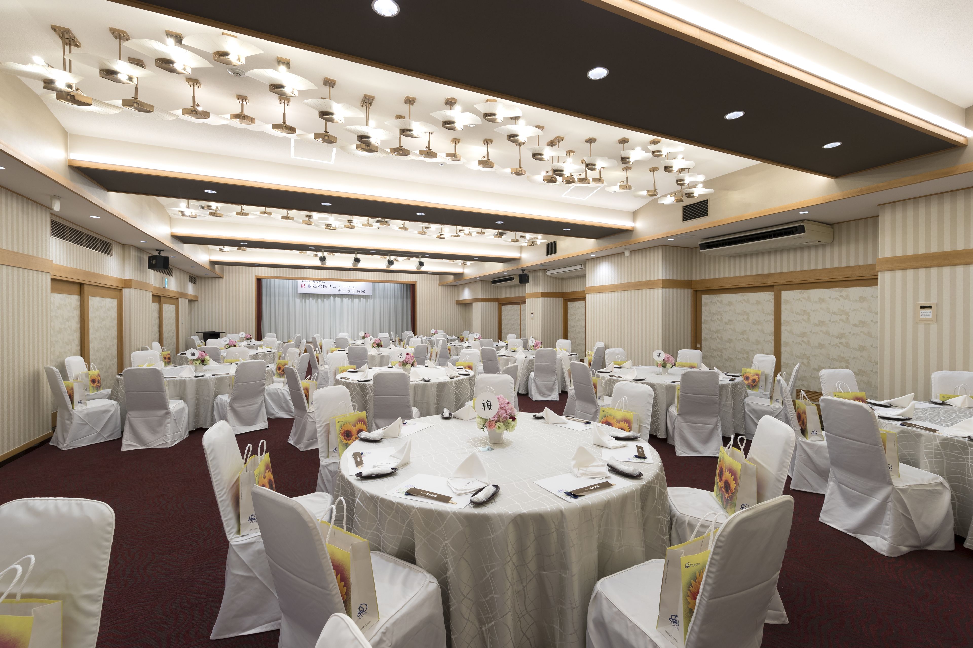 A large conference room with round tables, white chairs, and overhead lighting.