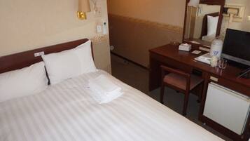 A hotel room with a bed, a desk, a chair, a television, and a minibar.