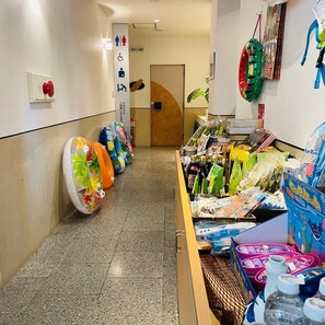 Un couloir avec un distributeur automatique et une étagère où sont exposés des objets colorés, le tout situé sur le côté droit.