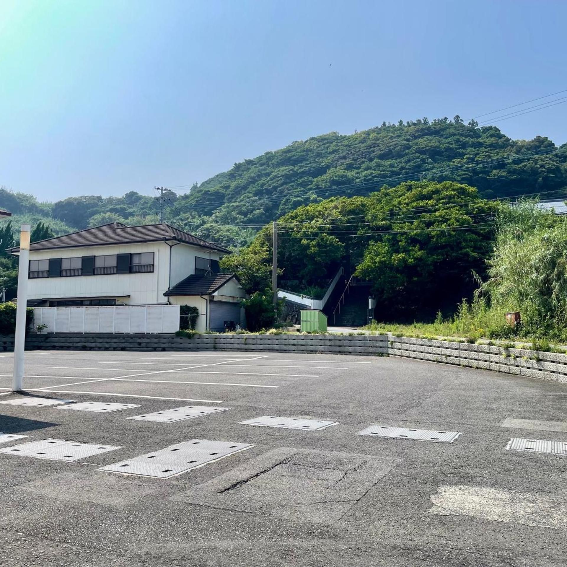 A parking lot with a building and a hill in the background.