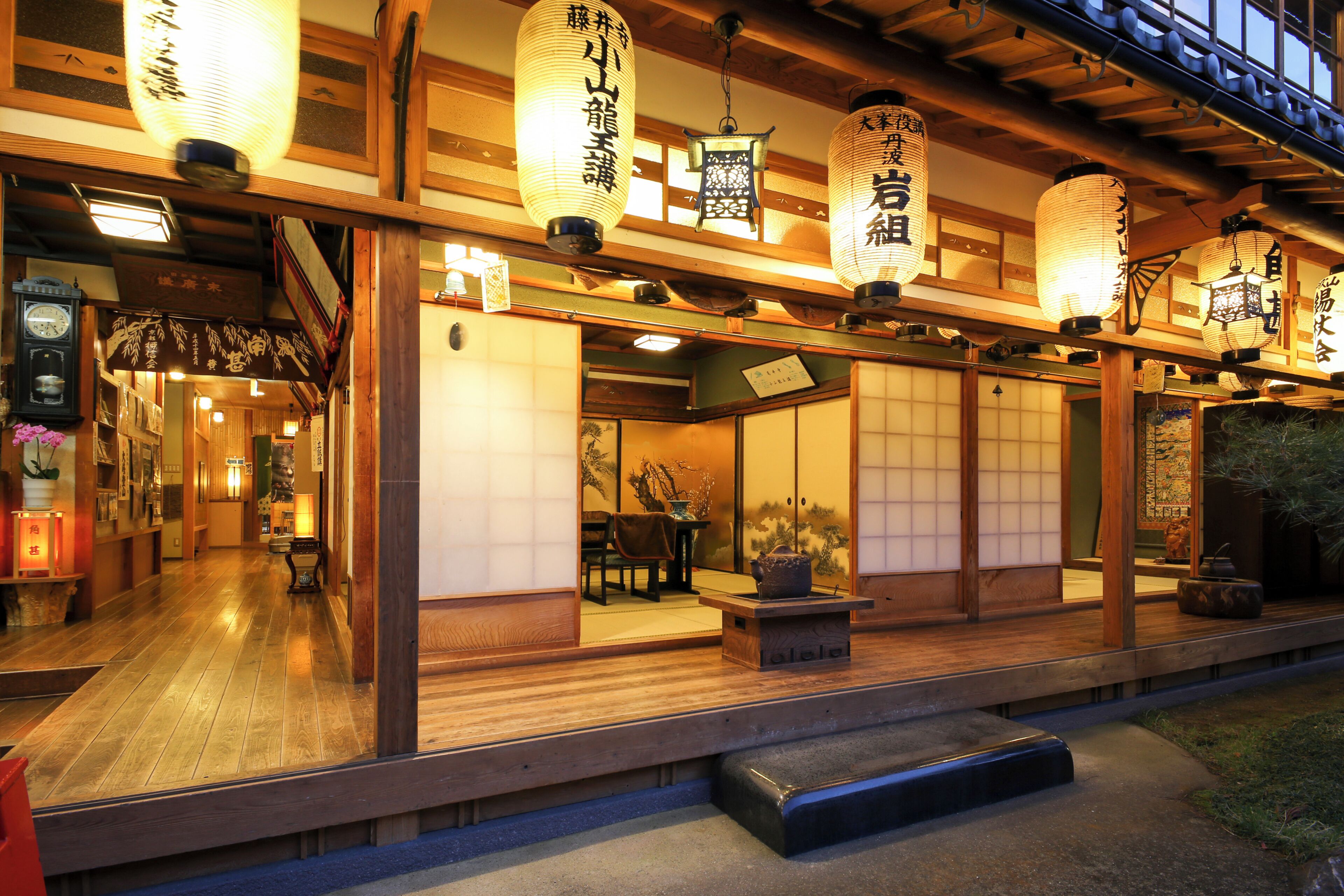 Een traditioneel Japans gebouw met houten vloeren, kamers met tatami matten en hangende lantaarns van papier.