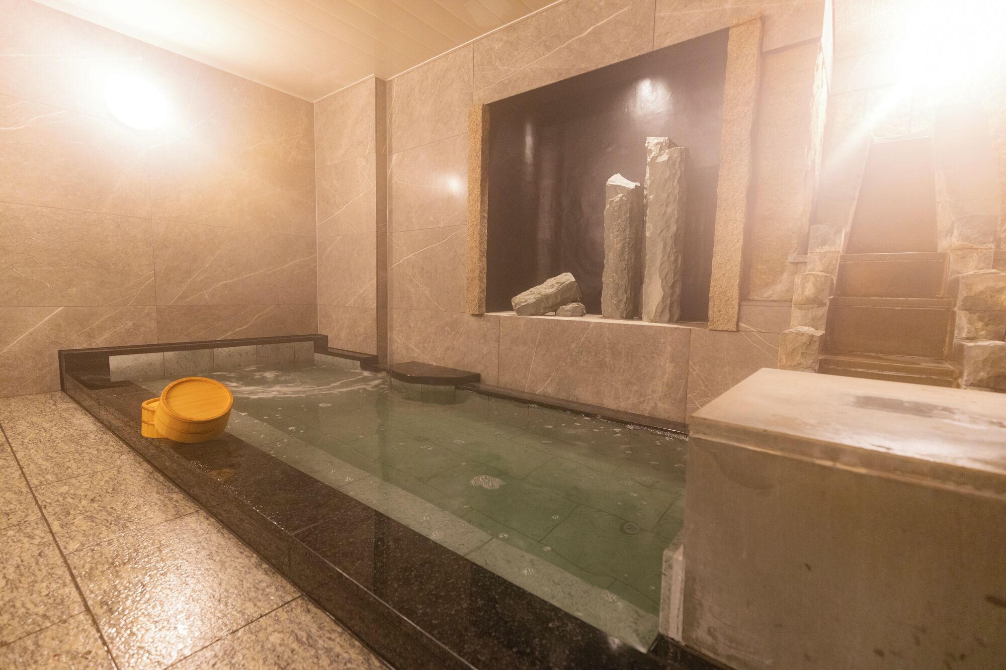 A spa area with a hot tub, a stone wall, and a window with a stone ledge.