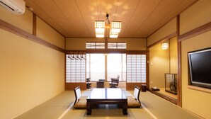 A traditional Japanese room with tatami flooring, a low table, and sliding doors.