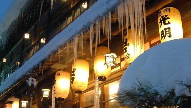 A building with traditional Japanese architecture, snow-covered exterior, and illuminated lanterns.