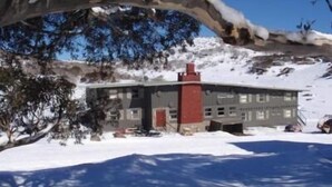 A building with a red chimney, surrounded by snow-covered ground and trees. - Swagman Chalet (Perisher Valley)